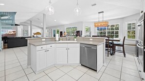 A spacious kitchen with white cabinetry, a central island, and a dining area with a table and chairs. - Pool House 1/2 Mile From Downtown Stuart (Stuart)