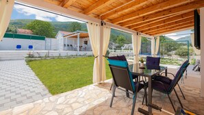 An outdoor patio with stone flooring, a wooden ceiling, and a view of a mountainous landscape. - Nice home in Pozla Gora (Pozla Gora)