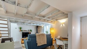 Uma sala de estar com sofá, mesa de jantar, televisão e lareira.