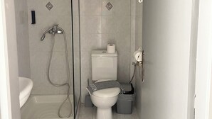 A compact bathroom with a shower, toilet, and sink. - Fairytale Apartments (Igoumenitsa)