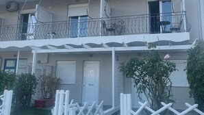 A two-story residential building with a balcony, a door marked with the number 4, and a white fence. - Fairytale Apartments (Igoumenitsa)