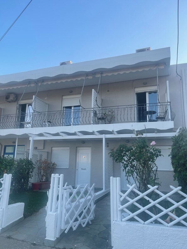 A two-story residential building with a balcony, a door marked with the number 4, and a white fence. - Fairytale Apartments (Igoumenitsa)