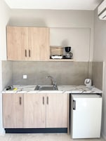Una cocina compacta con armarios de madera, un lavamanos integrado y un refrigerador blanco.