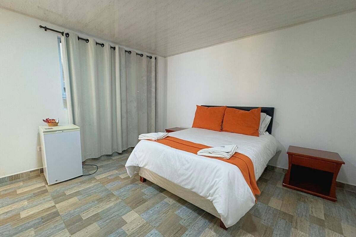 Un dormitorio con cama, mesita de noche, escritorio y silla.