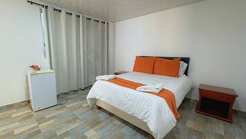 Un dormitorio con cama, mesita de noche, escritorio y silla.