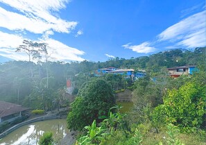 A view of a hillside with buildings, a curved water body, and dense greenery. - VillaLoren Club Social y Deportivo (San Antonio del Tequendama)