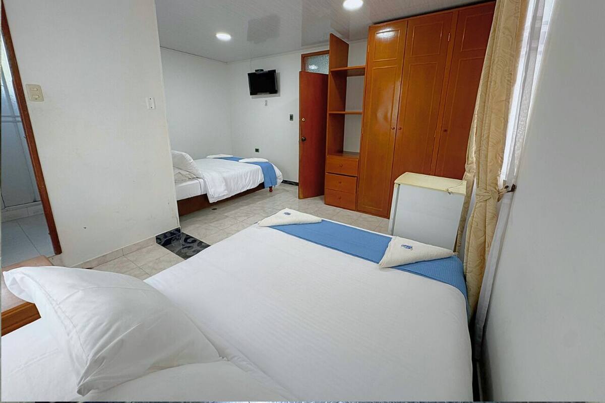 Habitación de hotel con dos camas, un armario, televisión y baño.