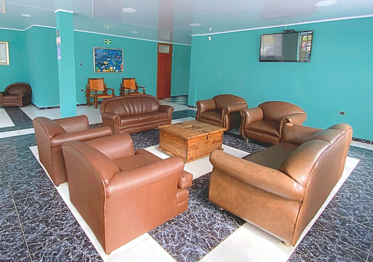 Eine Lobby mit braunen Ledersofas, die um einen Holztisch angeordnet sind, mit tealfarbenen Wänden und einem gefliesten Boden.