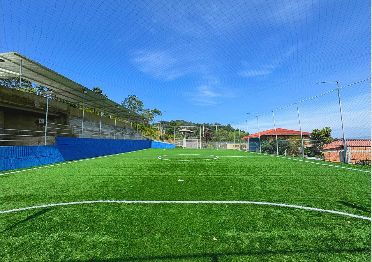Ein Sportplatz im Freien mit einem Tor, umgeben von einem Zaun und mit einem Dach.