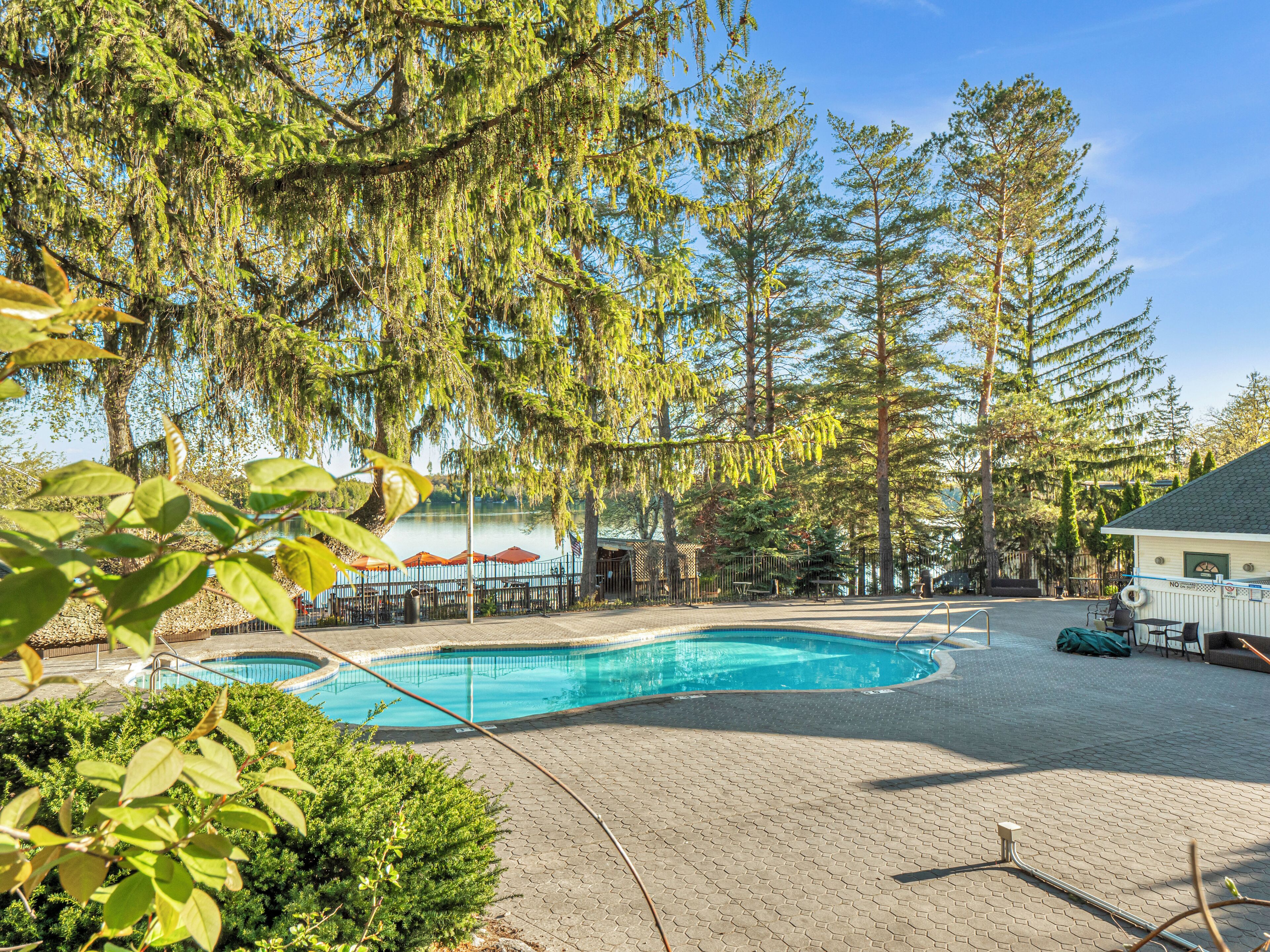Une piscine entourée d’arbres et un bâtiment doté d’un patio couvert.