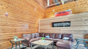 A cozy room with a brown leather sofa, two small tables, a coffee table, and a red bus model on a wooden wall. - First Floor Pet Friendly Queen Suite with Single Pull-out (Elkhart Lake)
