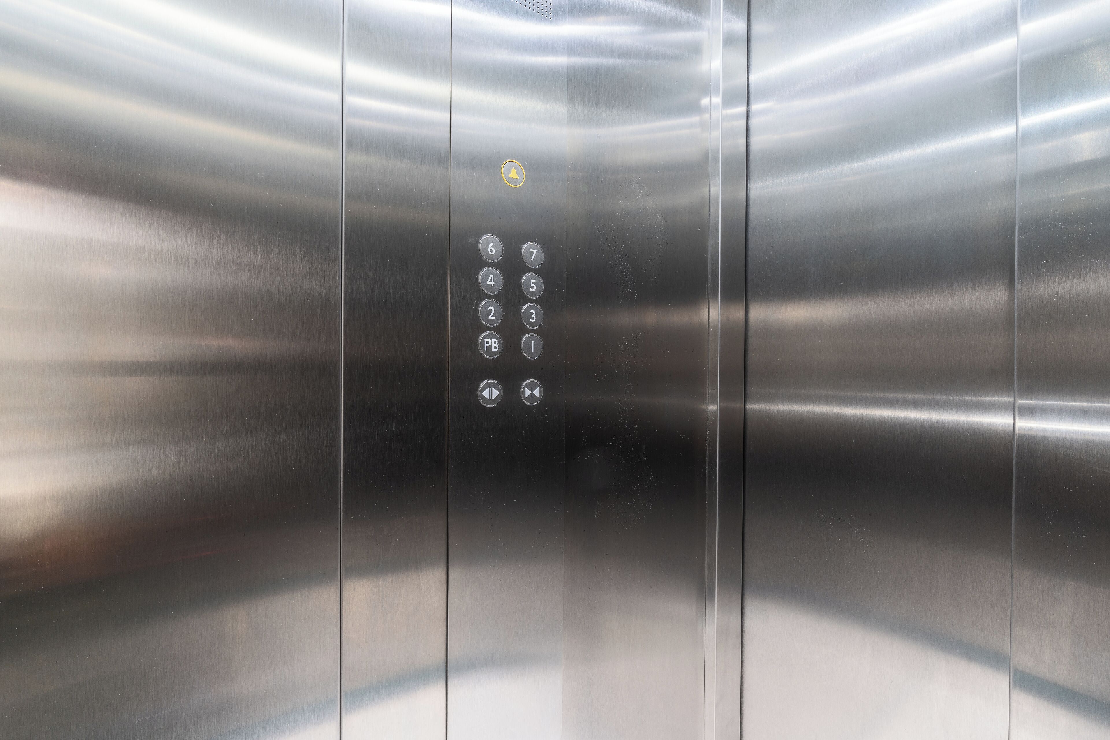 An elevator interior with a metallic finish and a control panel with numbered buttons.