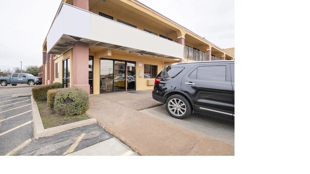 A building with a modern design, featuring a flat roof and large windows. There is a parking lot in front with a few cars parked. - Southern Comfort Hotel (Tulsa)