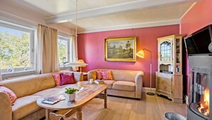Ein gemütliches Wohnzimmer mit einer Couch, einem Holztisch, einem Kamin und einem Bild an der Wand.