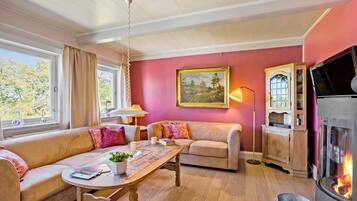 Un salon chaleureux avec un canapé, une table en bois, une cheminée et un tableau accroché au mur.