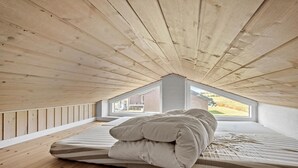 A bedroom with a sloped ceiling, wooden flooring, a bed with striped bedding, and a view through a window. - 4 bedroom lovely home in Faaborg (Faaborg)
