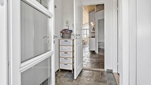 A narrow hallway with white doors, a stone-tiled floor, and a small wooden cabinet with drawers. - 4 bedroom lovely home in Faaborg (Faaborg)