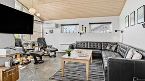 A modern living room with a leather sofa, a wooden coffee table, and a flat-screen TV. - 4 bedroom lovely home in Faaborg (Faaborg)