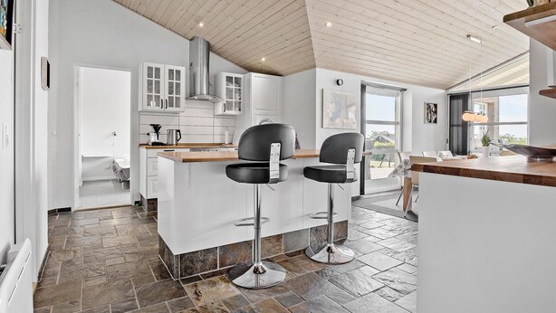 A modern kitchen with white cabinets, a wooden countertop, and two black bar stools. - 4 bedroom lovely home in Faaborg (Faaborg)