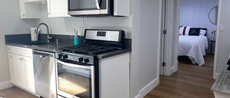 Una cocina moderna con armarios blancos, un microondas, una estufa y un horno.