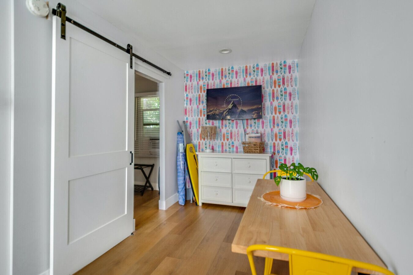 Un comedor con una mesa de madera, una silla amarilla y un armario blanco.