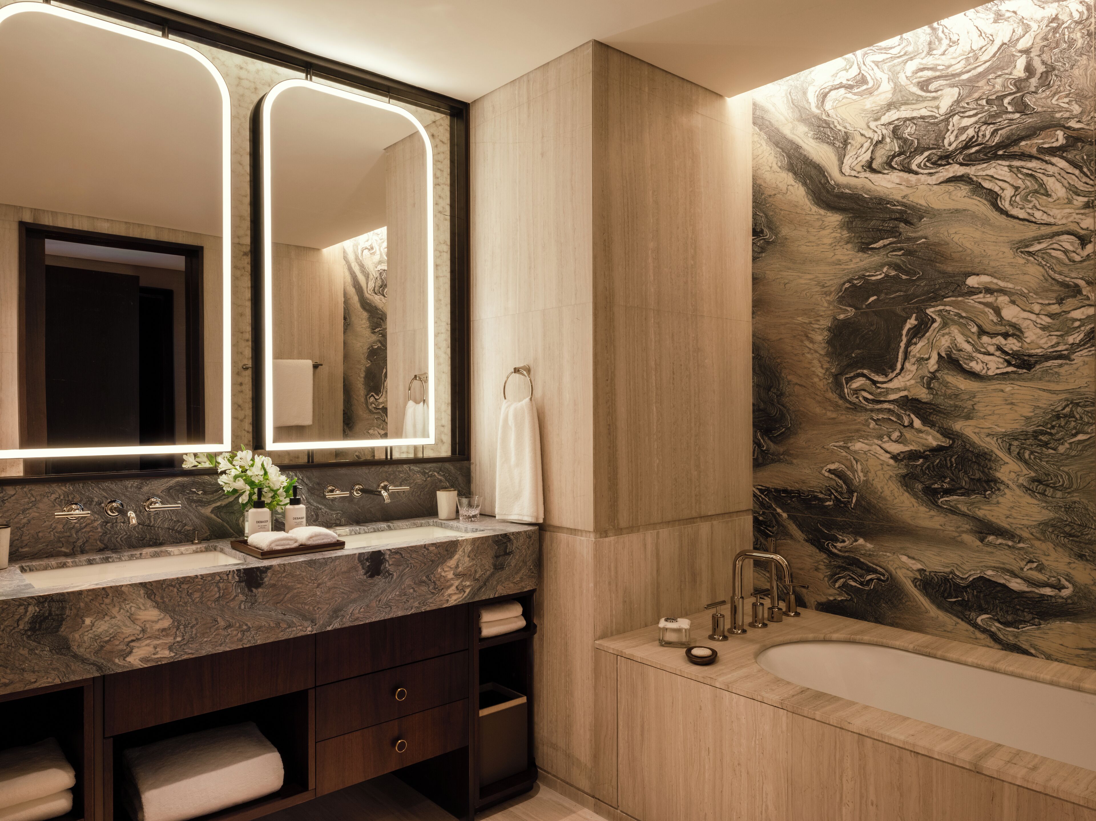 A modern bathroom with a marble vanity, a large mirror, and a wall mural.