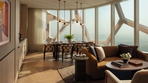 A modern living room with a dining area, large windows, and a view of the sea. - Rosewood Doha (Doha)
