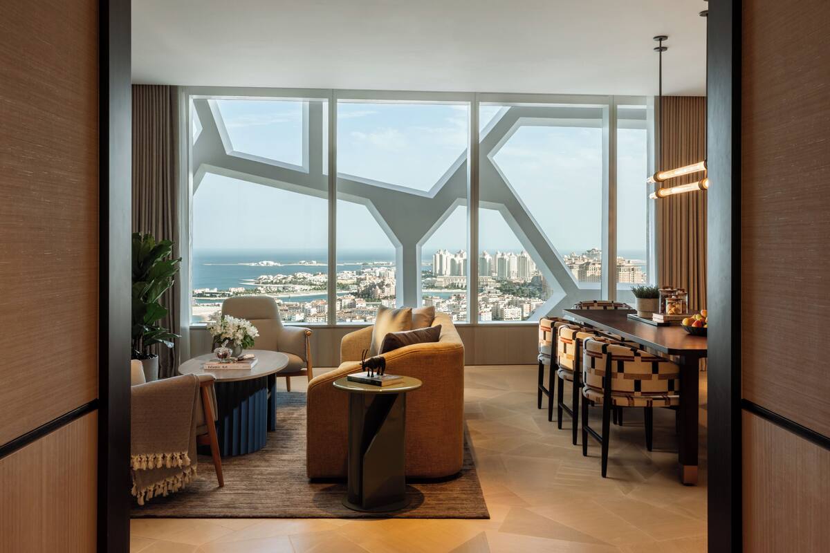 A modern living room with a panoramic city view, a dining area with a bar, and a large window with geometric framing.