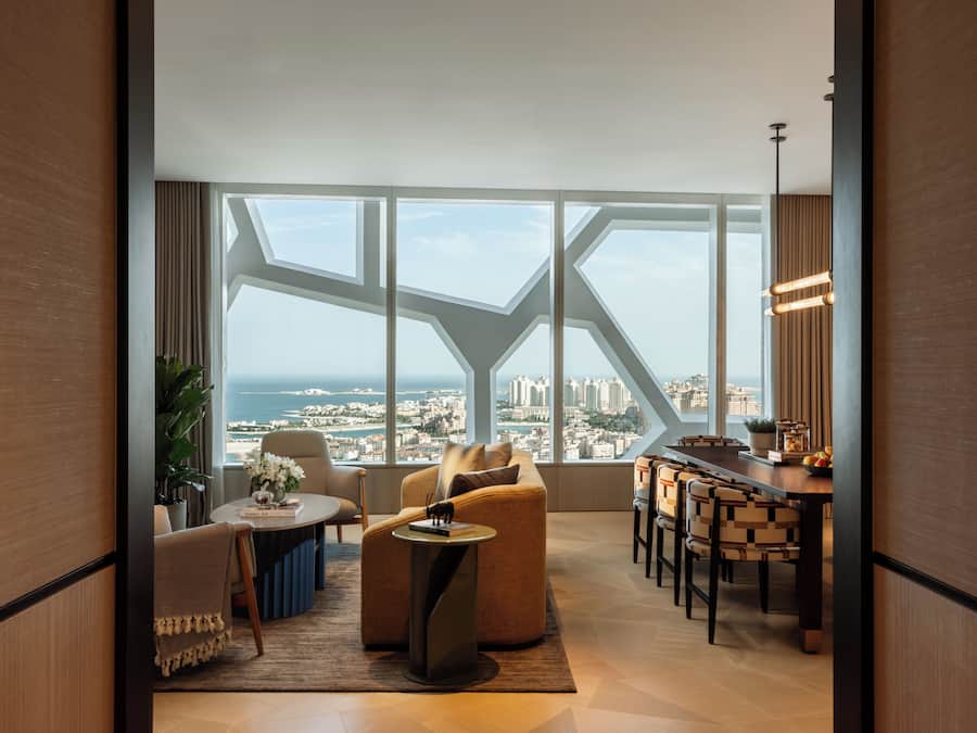 A modern living room with a panoramic city view, a dining area with a bar, and a large window with geometric framing.