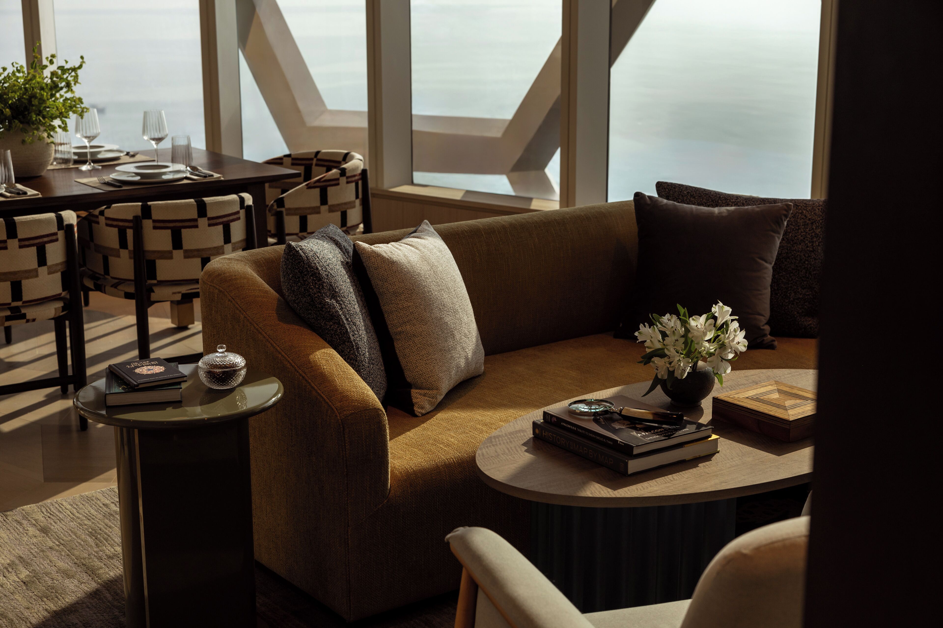 A modern living room with a sofa, a coffee table, and a dining area with a table set for two.