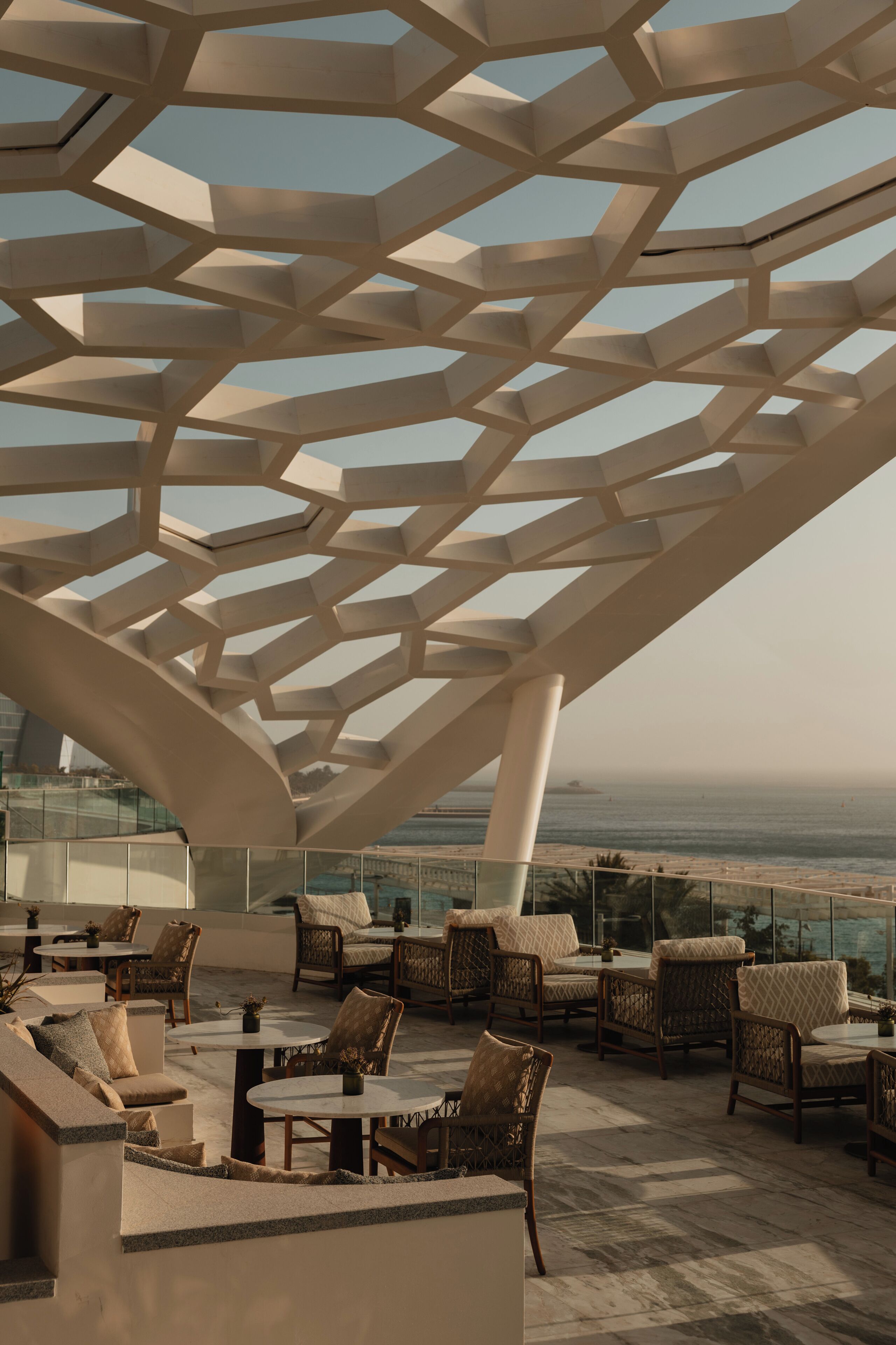 A rooftop terrace with geometric ceiling design, outdoor seating, and a view of the ocean.