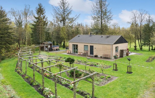A modern house with a garden, a hot tub, and a wooden pergola structure.