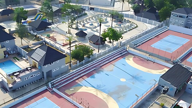 Vue aérienne d’un complexe sportif comprenant plusieurs terrains de basketball, une piscine et des bâtiments environnants.