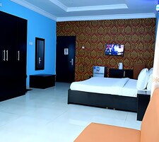 Quarto de hotel moderno com uma cama grande, televisão fixada na parede e um guarda-roupa.