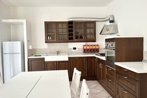 A kitchen with wooden cabinets, a white countertop, a built-in oven, and a stainless steel range hood.