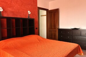 A bedroom with a bed, a dresser, a door, and a wall with a textured surface.