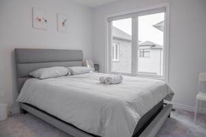 Un dormitorio con cama, ventana y vista a una casa.