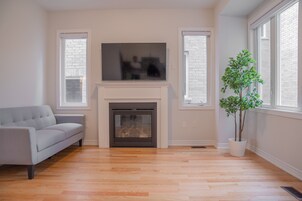 Una sala de estar con chimenea, un sofá gris y una planta en maceta.