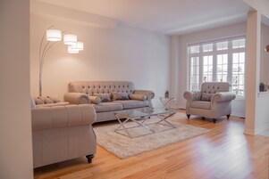 Una sala de estar con un sofá color beige, un sillón a juego y una mesa de centro de vidrio.