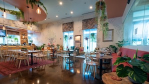 A cozy cafe with wooden tables and chairs, hanging plants, and a bar area. - Salted Tranquility at The Palms Of Destin (Destin)