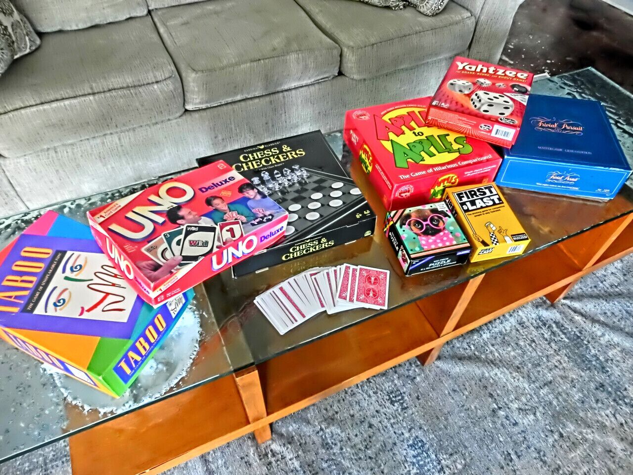 Ett soffbord i glas med olika brädspel, bland annat UNO, schack och dam, samt andra spel.