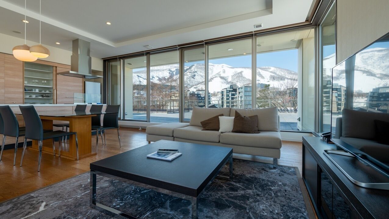 A modern living room with a sofa, coffee table, and dining area.
