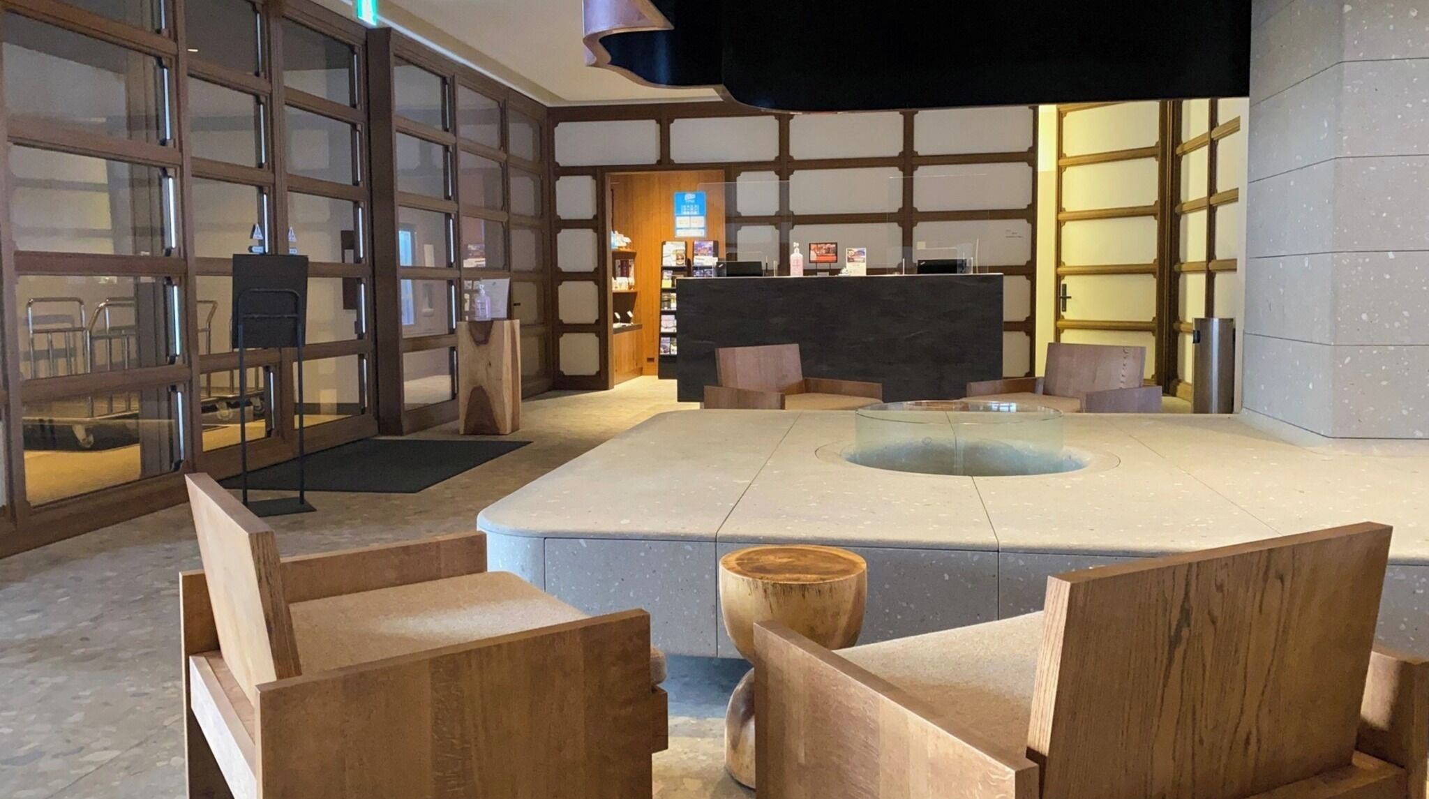 A modern lobby with a central seating area, wooden furniture, and a reception desk.