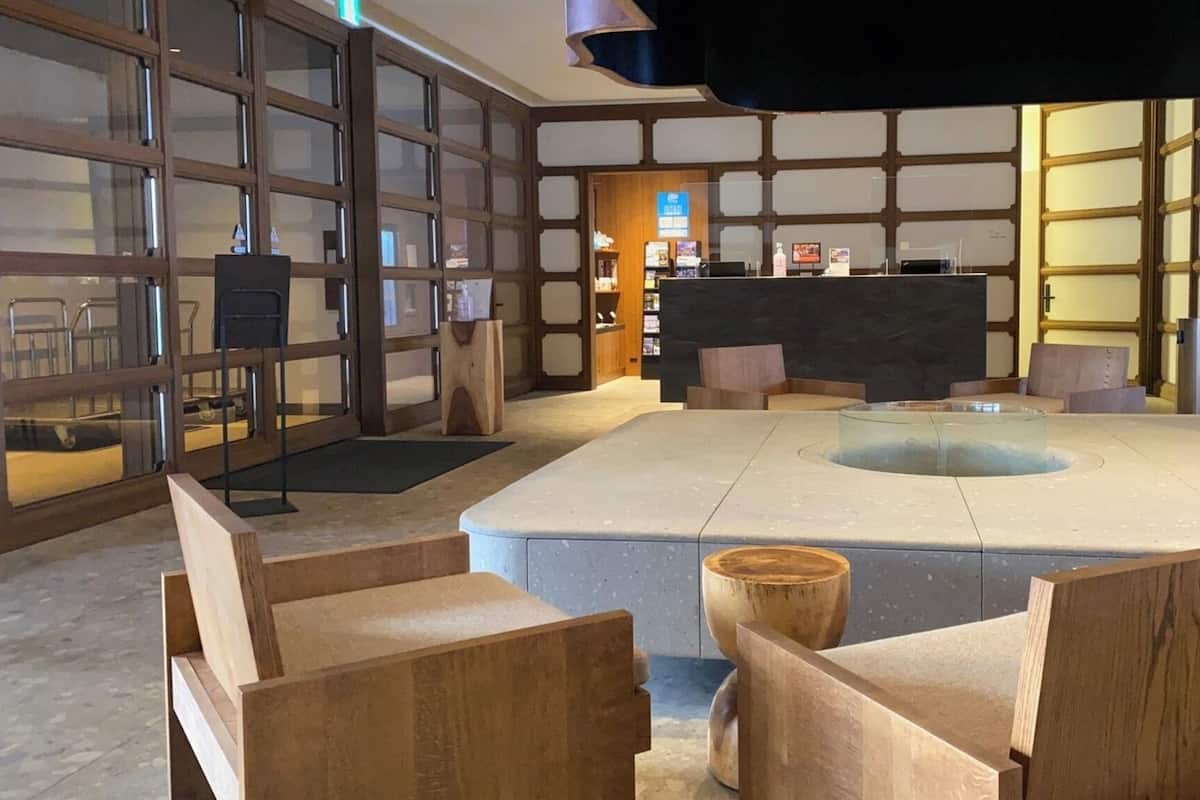 Un vestíbulo moderno con una zona de estar central, muebles de madera y una recepción.