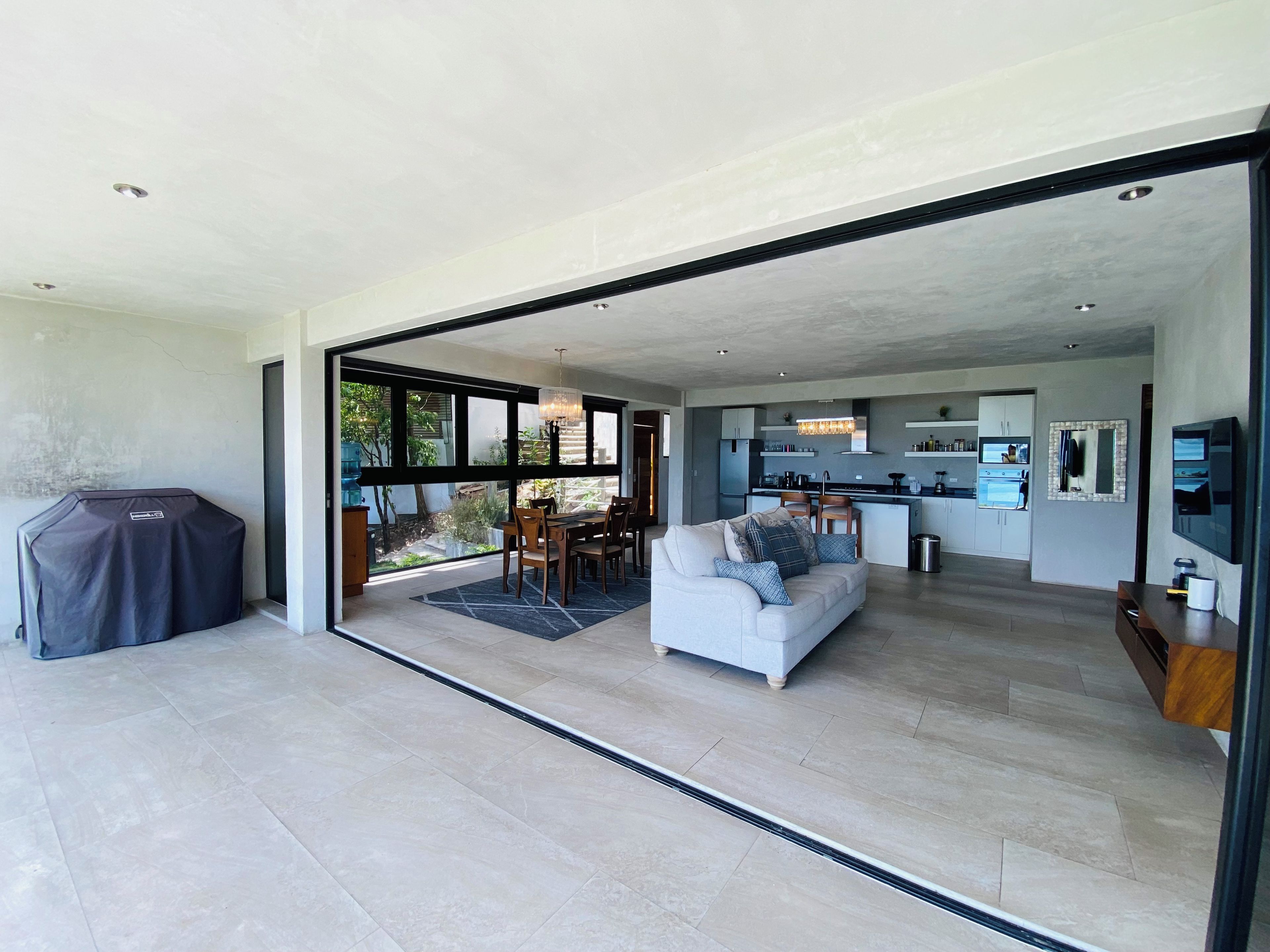Un espacio habitable moderno con comedor, cocina y un patio cubierto.