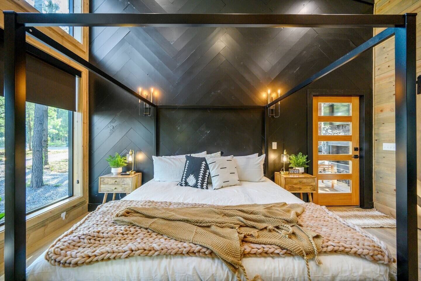 A modern bedroom with a large bed, wooden headboard, and a view through a glass door.