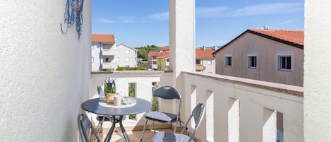 A balcony with a round table, two chairs, and a potted plant.