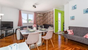 Una sala moderna con comedor, un televisor de pantalla plana y una pared de piedra.