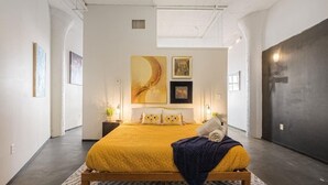 Une chambre à coucher moderne avec un grand lit, des œuvres d’art accrochées aux murs et un mur d’accent de couleur foncée.