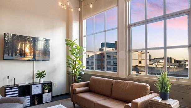 Un salon moderne avec une grande fenêtre, un canapé, une table basse et un téléviseur.